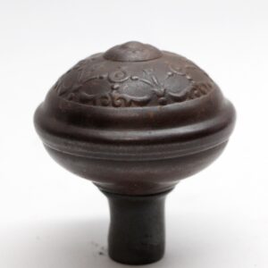 Close-up of a black cast iron passage door knob with an ornate domed top and short stem.