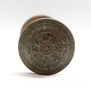Antique bronze door knob with an ornate circular eight-fold pattern and aged surface detail, shown front on as a single knob.