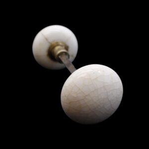 Pair of antique white ceramic door knobs with crackled glaze, shown with a spindle and two metal shanks on a black background.