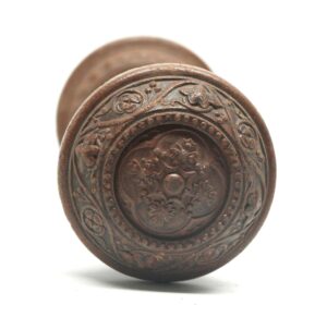 Victorian wood door knob with a concave center, beaded floral and scroll pattern, shown in a close-up front view.
