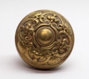 Art Nouveau brass entry door knob with ornate pressed floral scrollwork and a domed center.