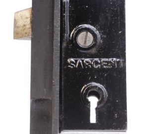 Close-up of a Sargent French door lock showing the black steel mortise faceplate with a slotted screw, keyhole, and brass latch bolt.