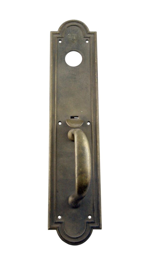 Art Deco bronze commercial door pull with an antique finish, a thumb latch, and a lock insert opening.
