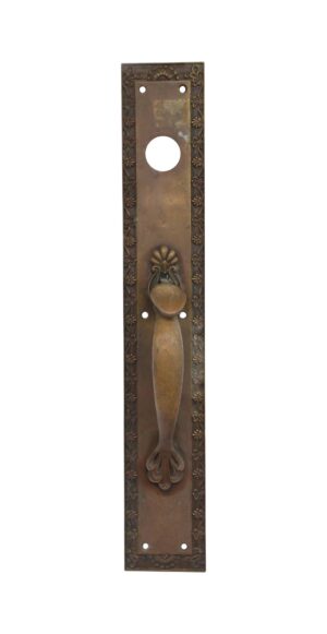 Neoclassical bronze entry door pull with a flower and shell design, thumb latch, and keyhole opening on a long plate.