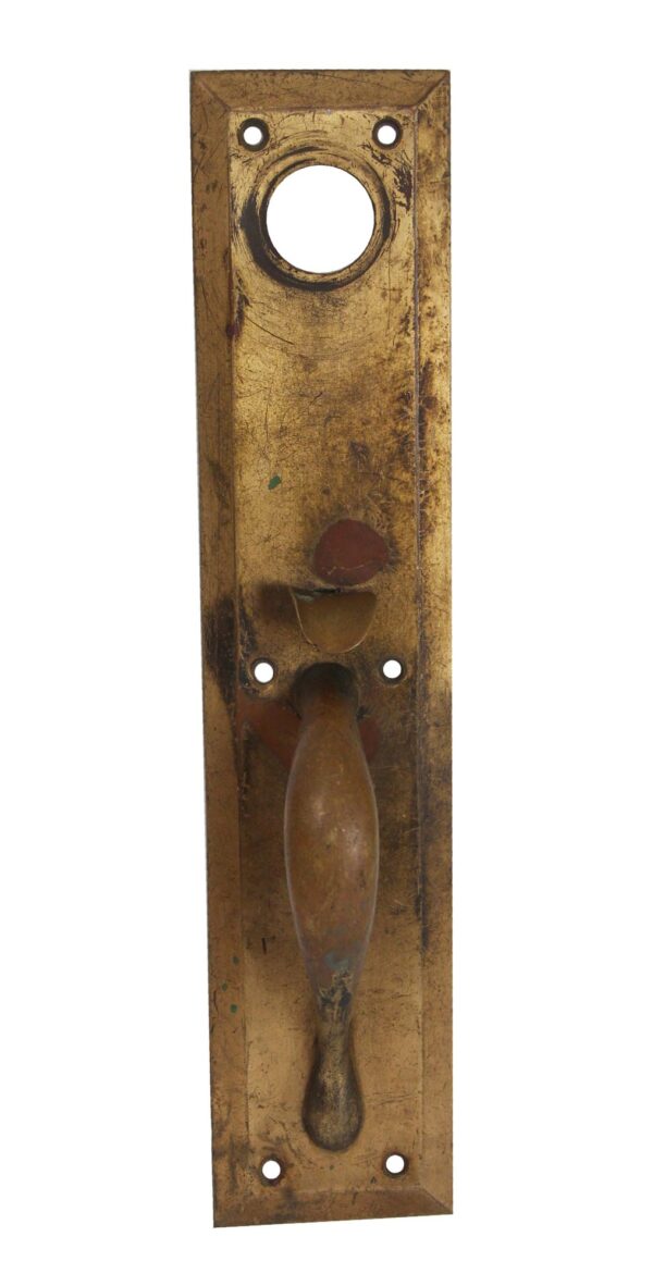 Antique brass door pull with a thumb latch, a large circular opening at the top, and a rectangular backplate with screw holes.
