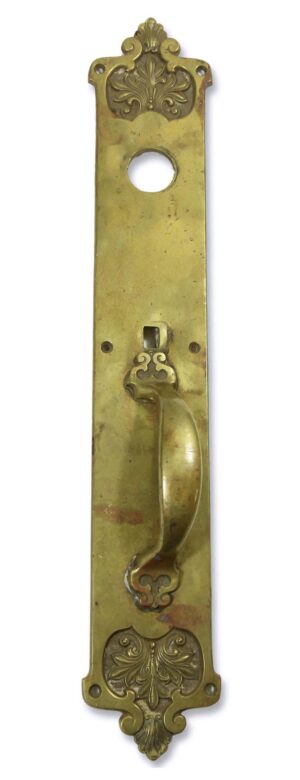 Romanesque brass door pull with an ornate backplate, a round lock hole, and a curved handle, shown front on.