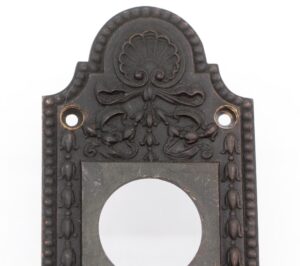 Antique bronze neoclassical door pull with leafy and tulip decoration, shown in a close-up of the upper section with mounting holes and a circular lock opening.