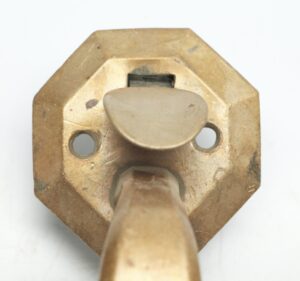 Antique bronze door pull with an octagon backplate, thumb latch, and visible mounting holes, shown in close-up front view.