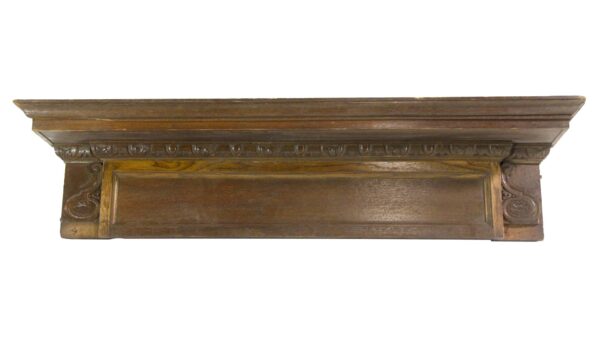 Carved oak door header pediment with egg and dart detail and a dark wood tone.
