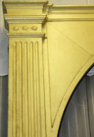 Close-up of a yellow painted entry arch door surround with fluted detailing and a curved arch section.