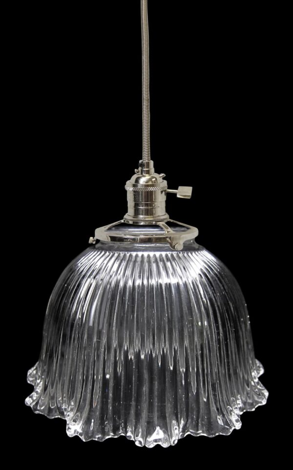Clear glass pendant light with a ribbed Holophane-style globe and metal fitter on a cord.