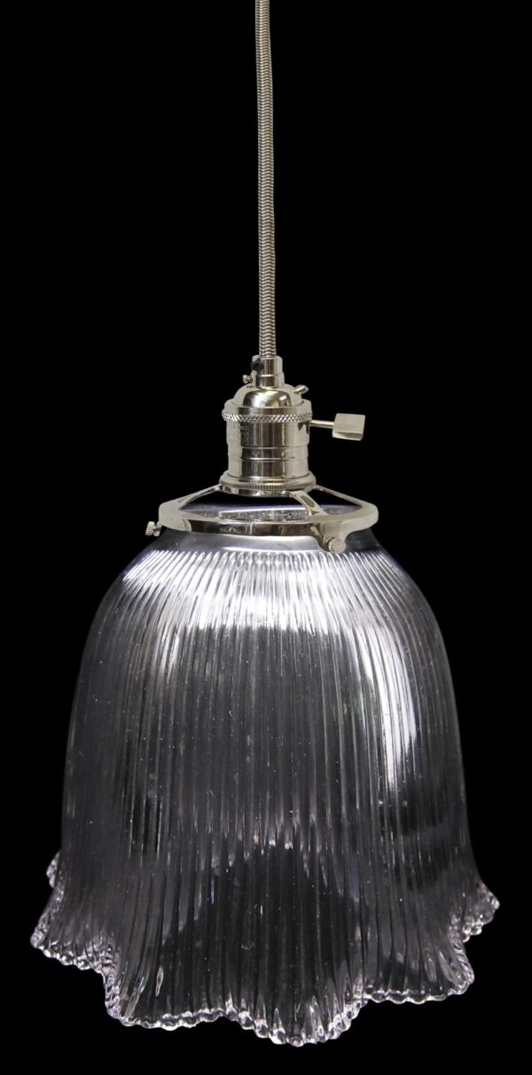 Clear glass pendant light with a ribbed Holophane globe and metal fitter shown in close-up on a dark background.