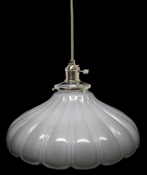 White milk glass pendant light with a fluted shade, polished nickel fitter, and cloth cord shown in close-up.