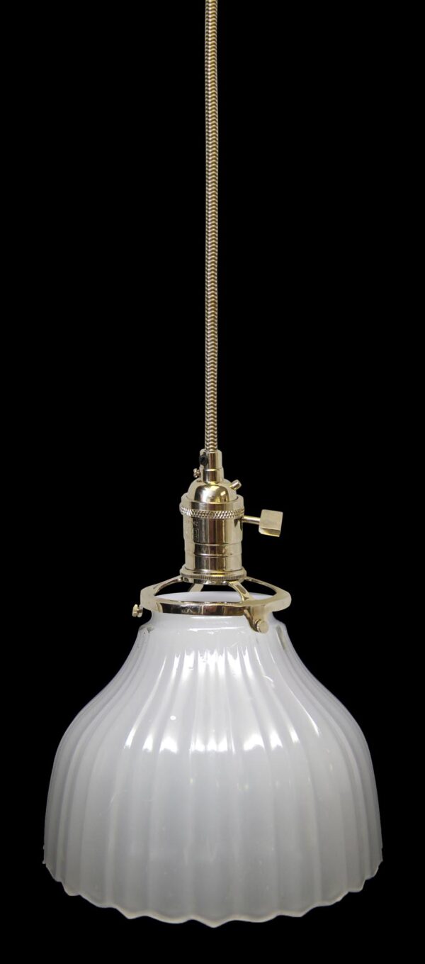 Pendant light with a fluted white milk glass shade and polished nickel fitter on a braided cord.