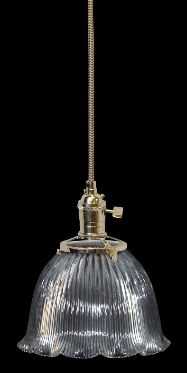 Clear glass pendant light with a ribbed Holophane globe and a metal fitter on a braided cord.