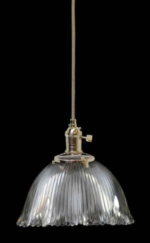 Clear glass pendant light with a ribbed Holophane-style shade and metal fitter hanging from a braided cord.