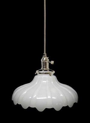 Pendant light with a fluted milk glass shade and polished metal fitter hanging from a cord.