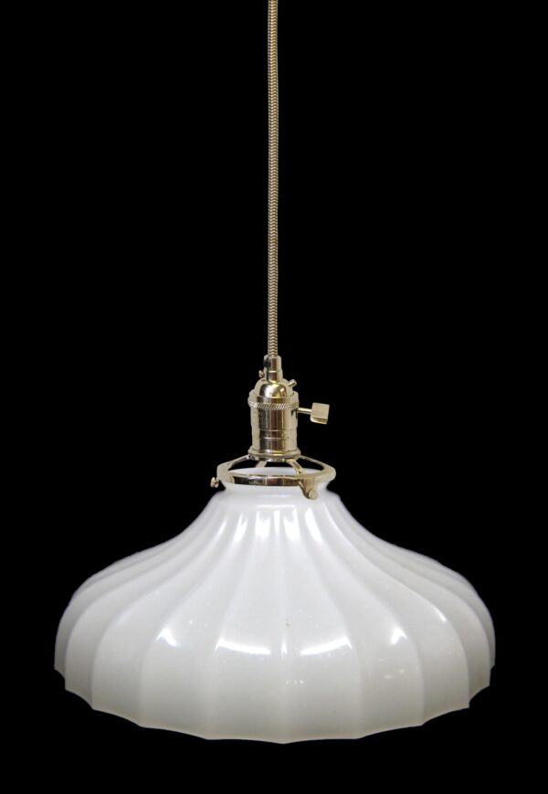 Pendant light with a fluted white milk glass shade and a polished nickel fitter suspended from a braided cord.
