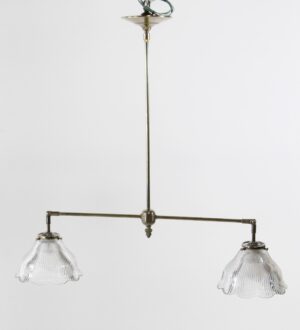 Double pendant light with an antique brass frame and two clear ruffled glass shades hanging from a central rod.