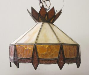 Tiffany-style stained glass pendant light with amber, orange, and burgundy panels and a faceted crown, shown in a close-up view.