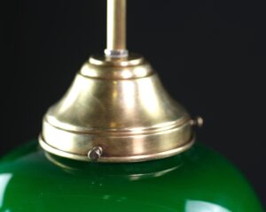 Close-up of a brass pendant light with a green glass shade and a visible top finial.