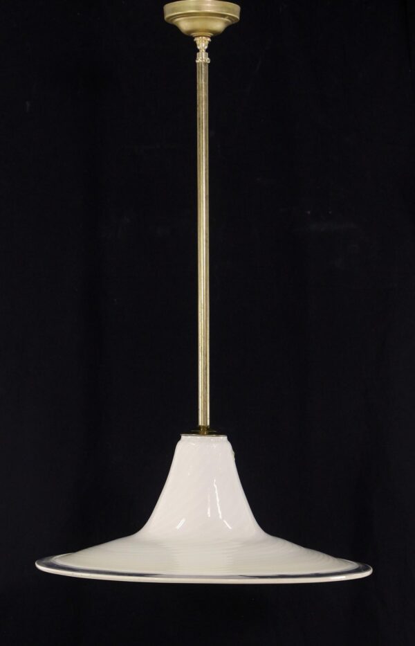 Pendant light with a long antique brass pole and a wide hand-blown swirled glass shade.