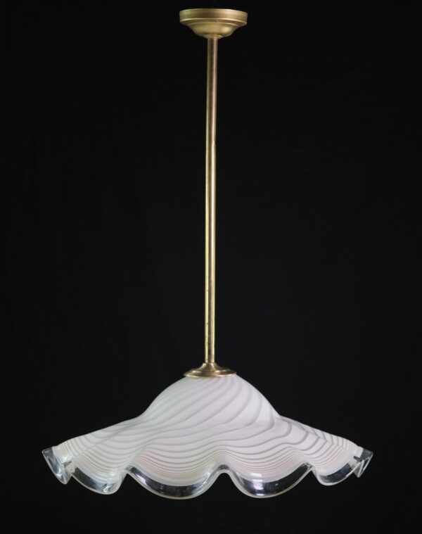 Glass pendant light with an antique brass rod and a rippled white shade with a clear scalloped brim.
