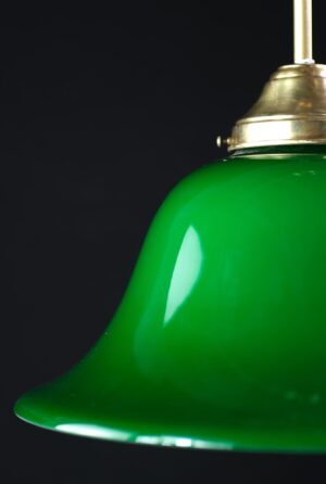 Close-up of a green glass pendant light with an antique brass fitting and pole.