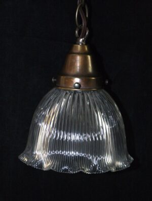 Clear prism glass pendant light with a bronze-toned fitter and hanging loop, shown in a close-up view of the shade and top hardware.