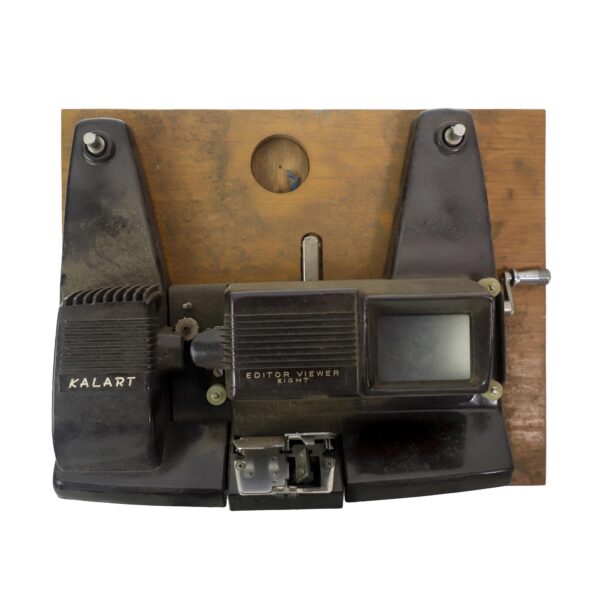 A vintage 8 mm film editor viewer with a black bakelite body mounted on a dark wood base board, shown front on with the built-in splicer at the front.