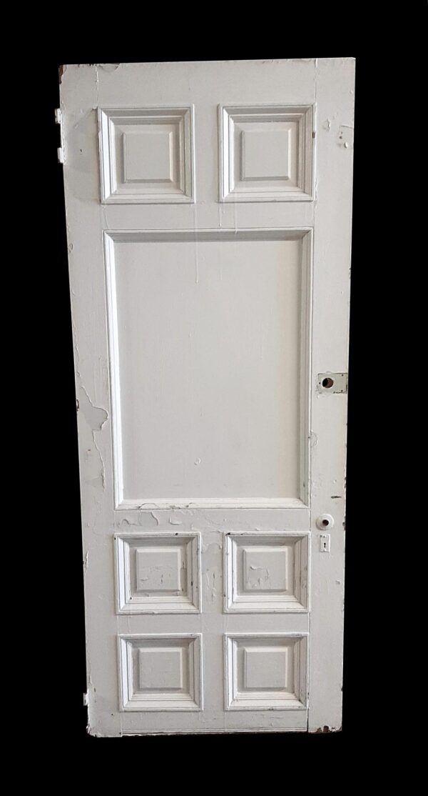 Antique wood entry door with seven raised panels, shown in white and slightly worn with visible edge damage and peeling paint.