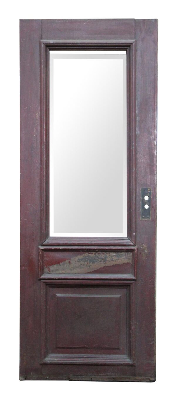 Antique entry door with one narrow beveled glass panel and two wood panels, shown in dark wood tone on one side with a visible hardware plate.