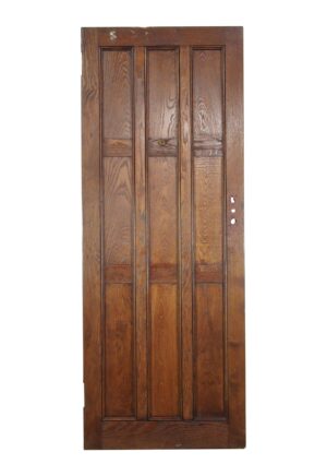 Arts and Crafts oak entry door with nine panels and a dark wood tone, shown full length with visible age wear and hardware holes on one side.