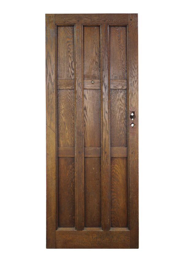 Arts and Crafts oak entry door with nine panels, shown front on with visible age wear and a door knob opening on the right edge.