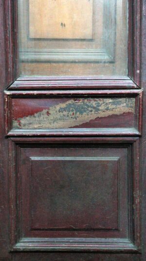 Antique entry door with one narrow beveled glass panel above two wooden panels, shown in a dark wood tone with visible worn paint on the center section.