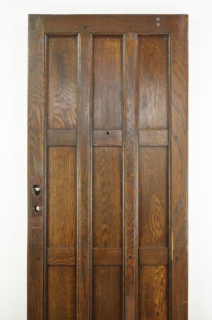 Arts and Crafts oak entry door with a dark wood tone, shown front-on with three vertical panels visible and cutouts for hardware on the left side.
