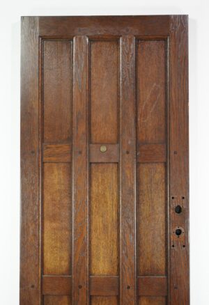 Arts and Crafts oak entry door with nine panels, shown front view with visible lock holes and aged wear in a dark wood tone.