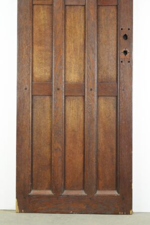 Arts and Crafts oak entry door with a dark wood tone, shown front on with vertical panels and predrilled hardware openings on the right side.