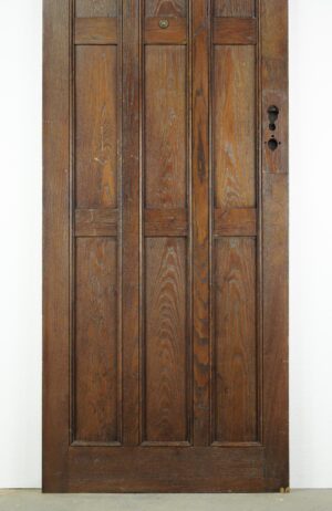 Arts and Crafts oak entry door with three vertical panels, a dark wood tone, and an exposed lock cutout on the right side.