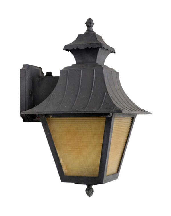 Black exterior sconce with an amber ribbed plastic lens and decorative finial details.