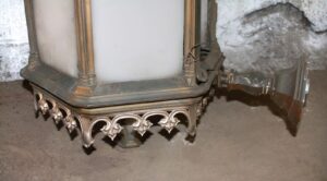 Cast bronze Gothic exterior sconce with glass panels and ornate lower trim, shown in a close-up side view.