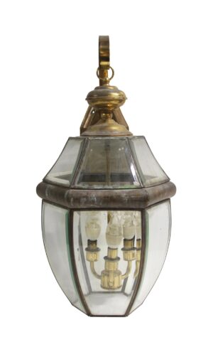 Traditional exterior lantern wall sconce with antique brass finish and clear beveled glass, shown with three candle-style lights and a hanging loop at the top.