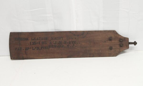 Antique reclaimed wooden fan blade with a dark wood tone and stenciled lettering, shown horizontally with metal hardware at one end.