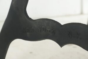 Close-up of a black cast iron table leg with the embossed words NEW YORK visible on the side.
