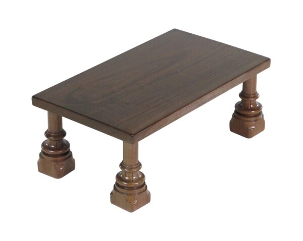 Dark wood tone walnut foot stool with a rectangular top, turned legs, and square feet.