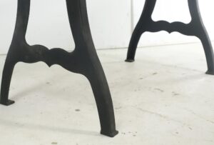 Close-up of black cast iron table legs with the lower support bar visible on a dining table.