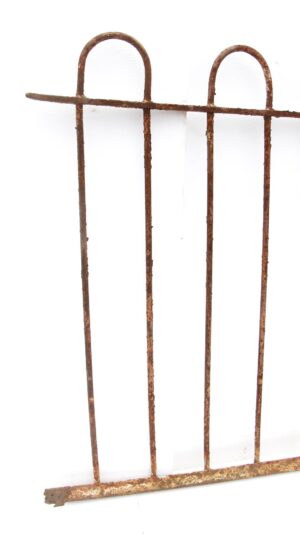 Heavily rusted wrought iron fence section with looped bars and a missing section.