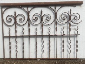 Small wrought iron fence section with scrollwork and vertical bars, shown front view as a decorative panel.