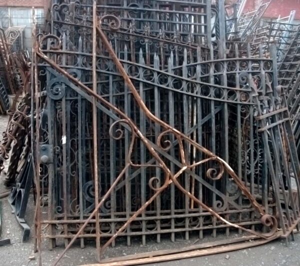 Pair of giant wrought iron building brackets with ornate scrollwork and pointed tips, shown stacked together at a slight angle.