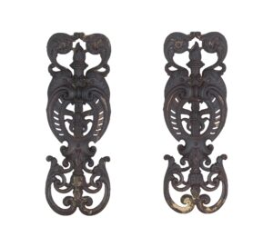 Pair of ornate cast iron balustrades with figural and torch details, shown side by side.